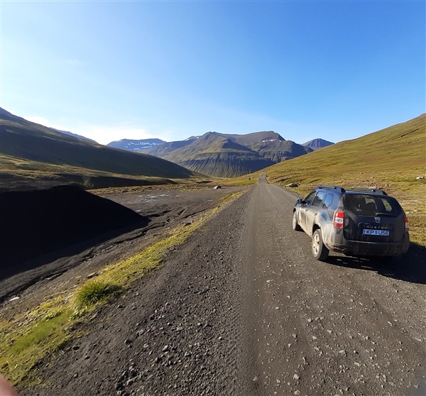 Een auto op een gravelweg in bergachtig gebied met mooi weer