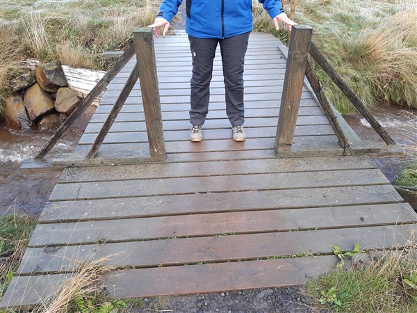 Een persoon laat de breedte zien van een doorgang voor rolstoelen bij een uitkijkpunt