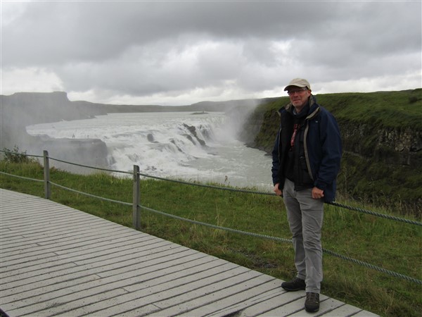 Man staat bij een waterval op IJsland