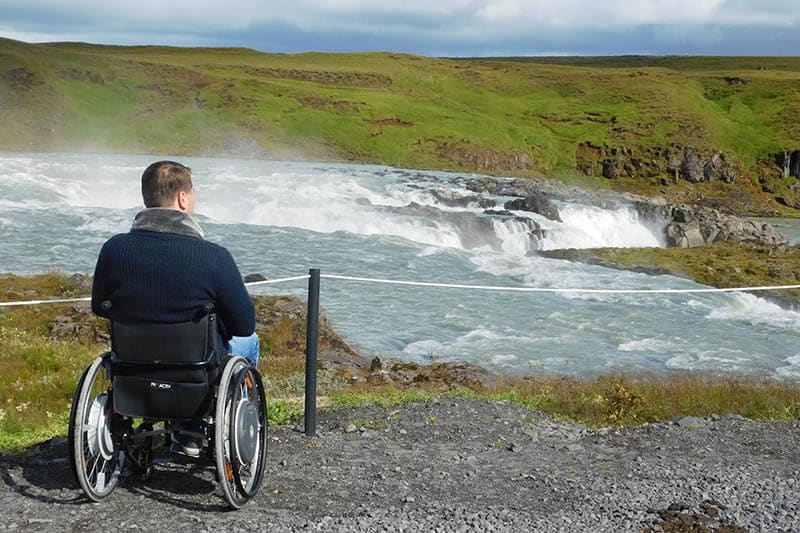 Een man in een rolstoel bekijkt watervallen op IJsland