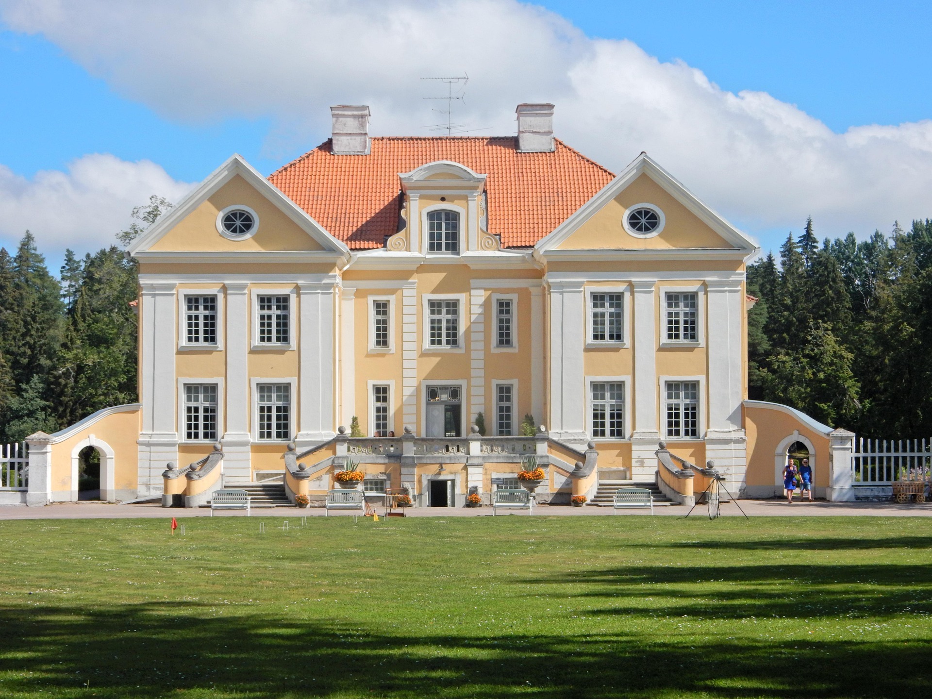 a large building with a lawn and trees in the background