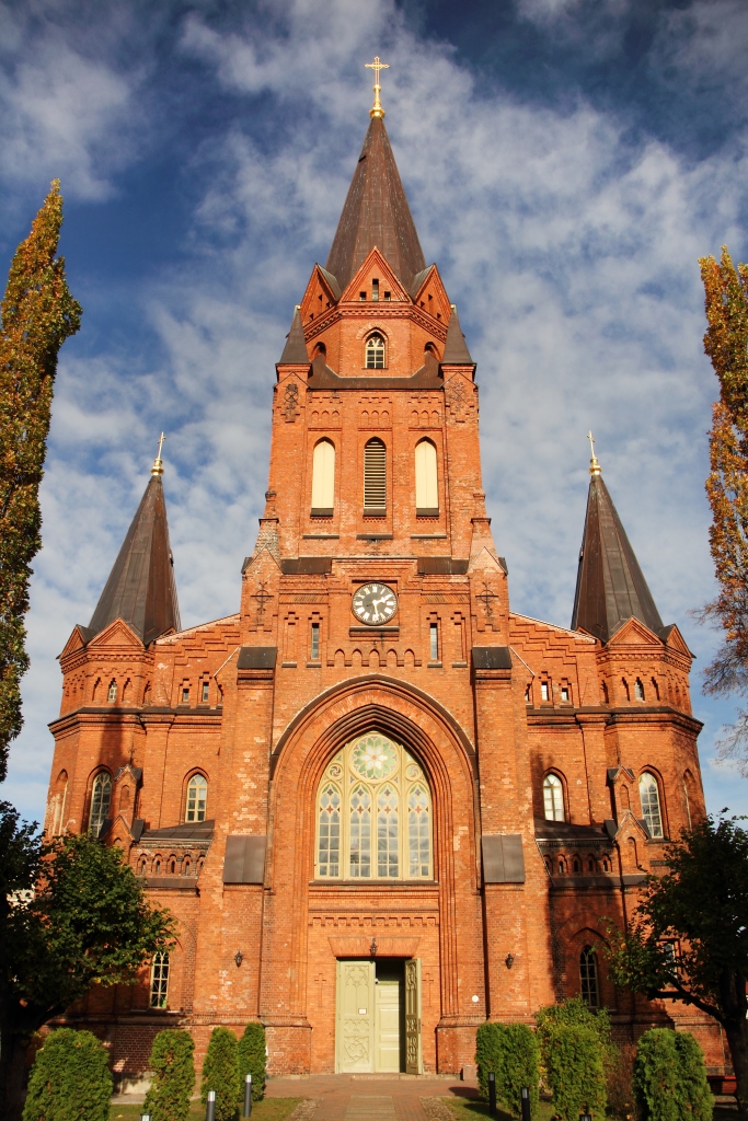Een kathedraal met rode bakstenen in een groene omgeving