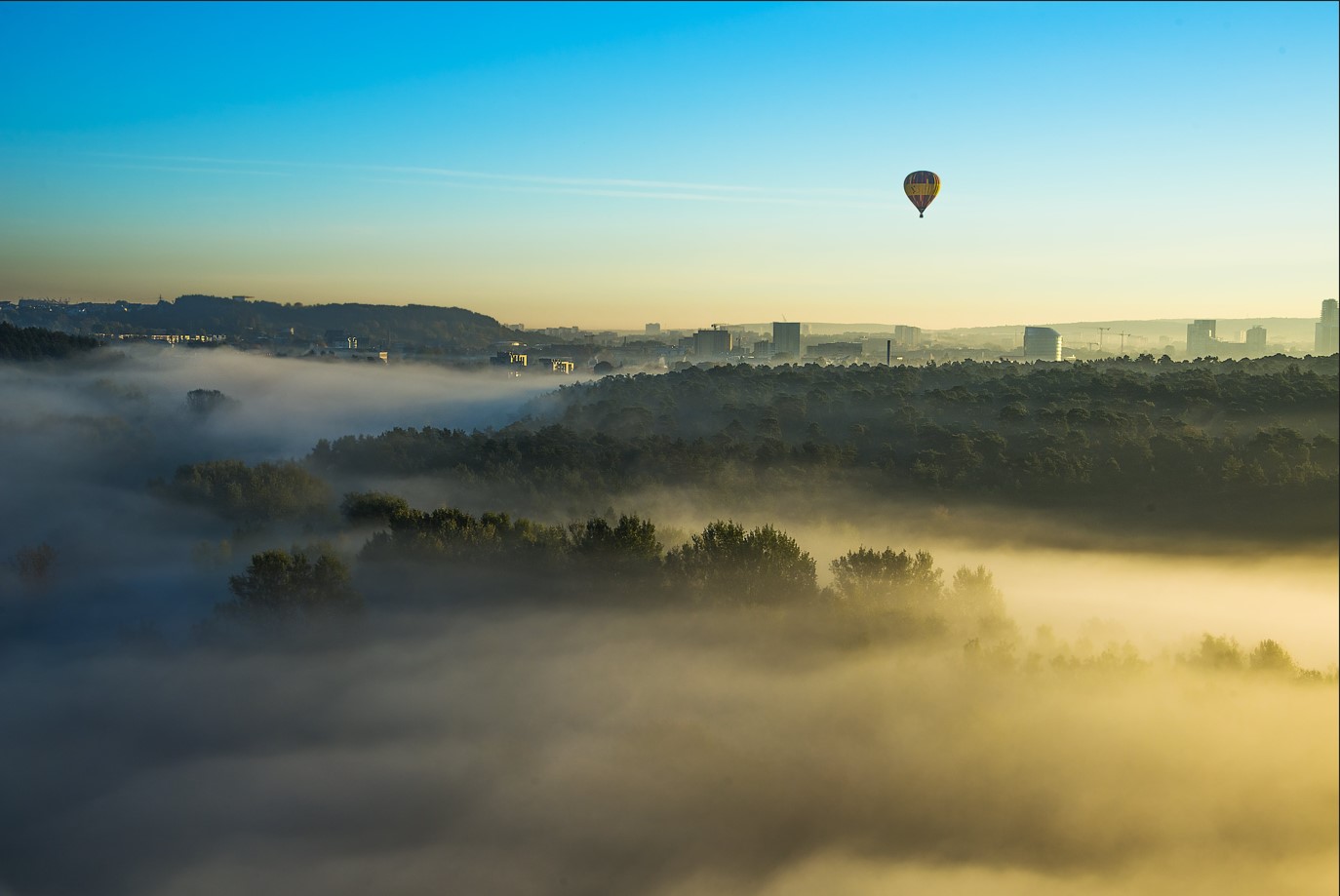 luchtballon boven een stad in de mist