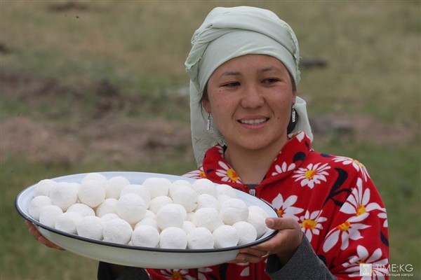 Een vrouw draagt een grote schaal met een tradioneel gerecht