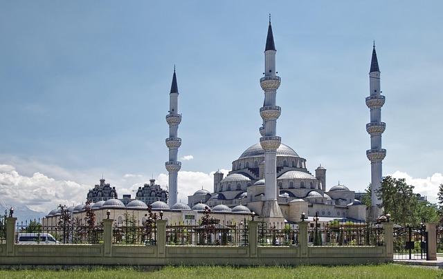 Een moskee met koepels en minaretten met bergen in de achtergrond