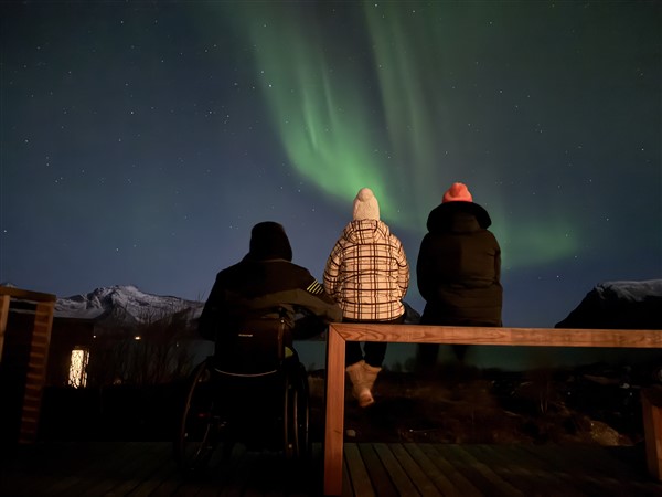 Ro3 mensen waarvan 1 in een rolstoel kijken naar het noorderlichtlstoel Turismo Adaptado V3 Lofoten (14)