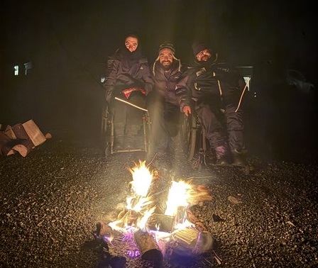 Mensen in een rolstoel bij een vuur buiten in de winter