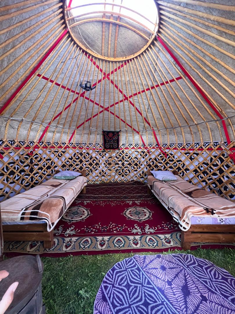 2 bedden met een tapijt er tussenin in een yurt