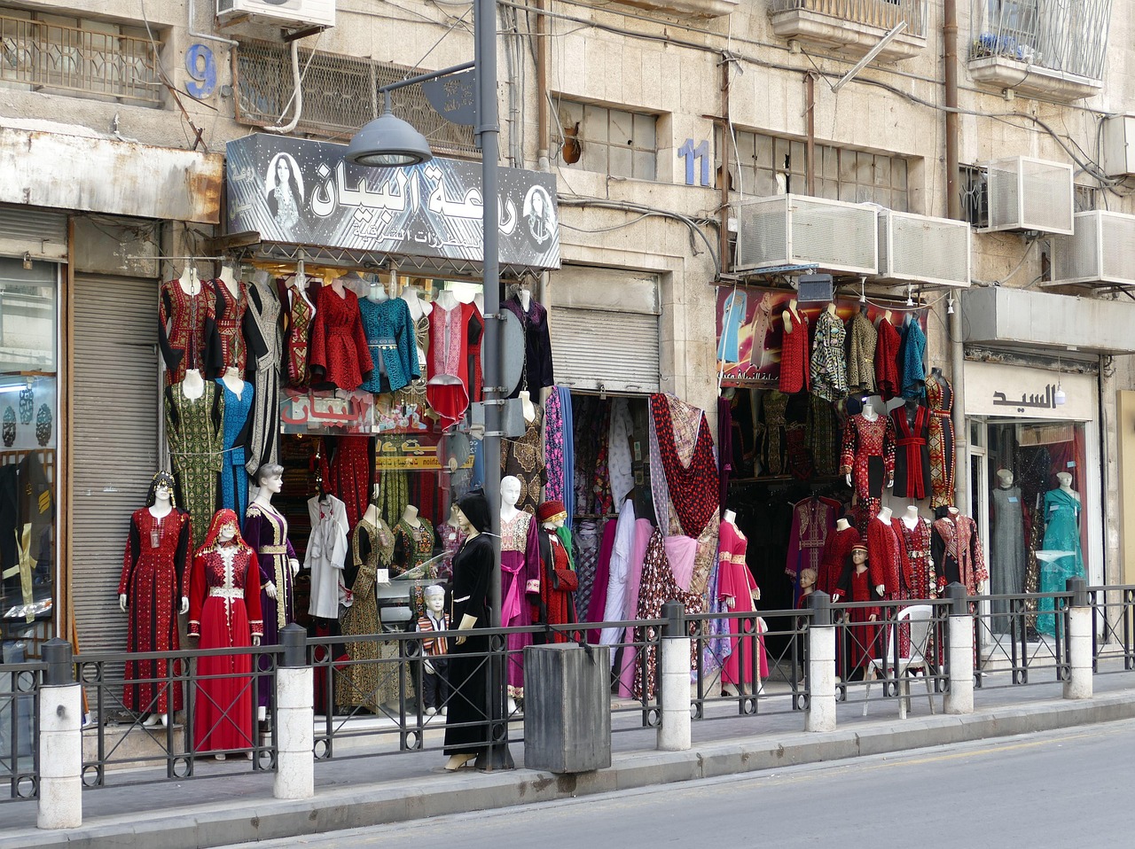 Een kledingwinkel hangt kleding tot hoog aan de buitengevel in Amman