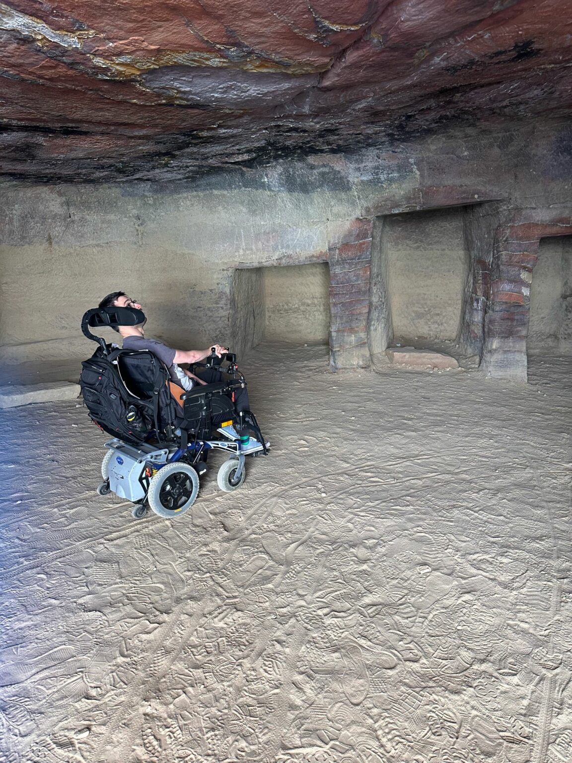 Man in een rolstoel bekijkt het plafond van een historisch bouwwerk uitgehouwen in de rotsen