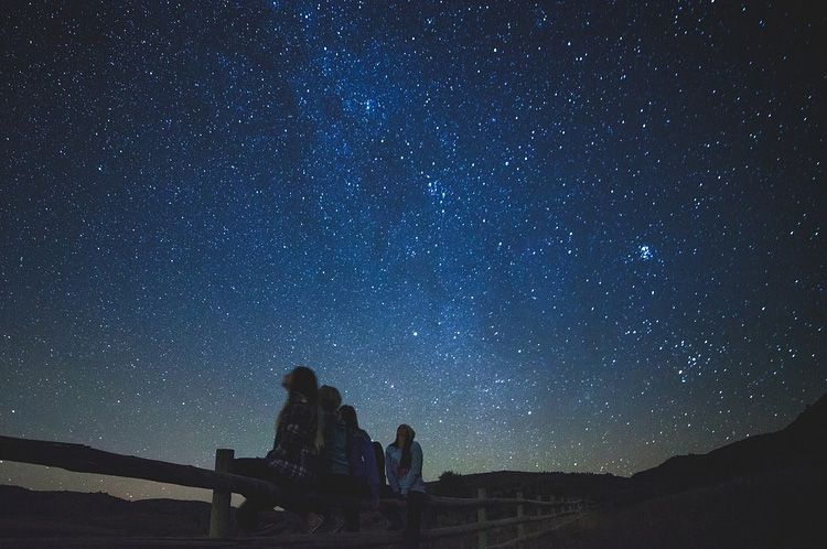 Mensen zitten op een rij te kijken naar de Melkweg