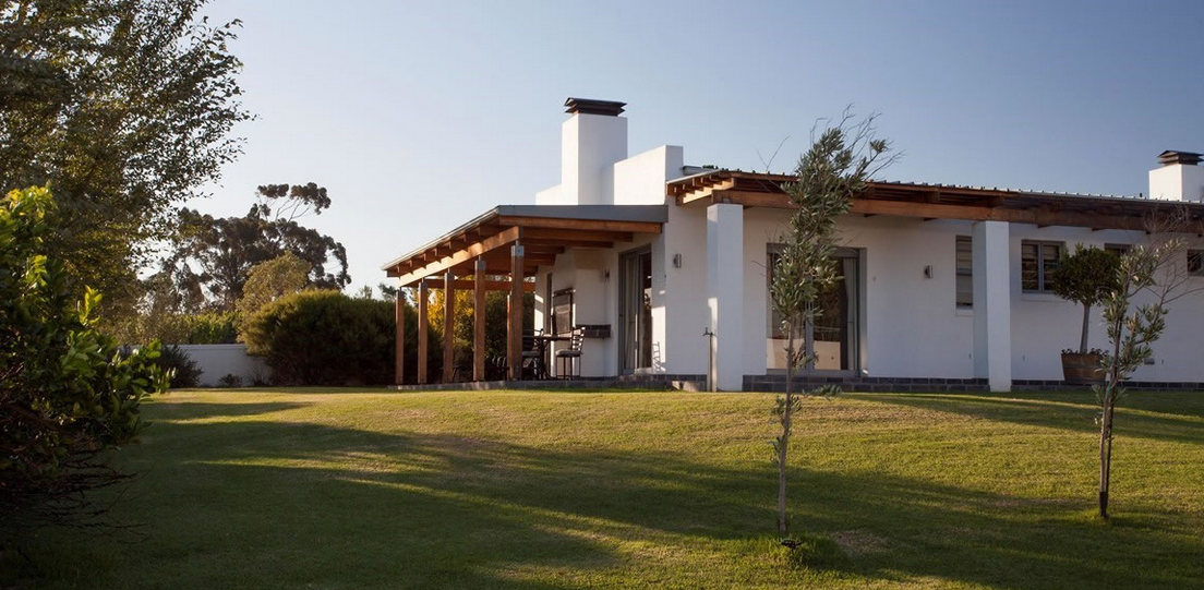 Een gastenverblijf op een heuveltje met een grasveld